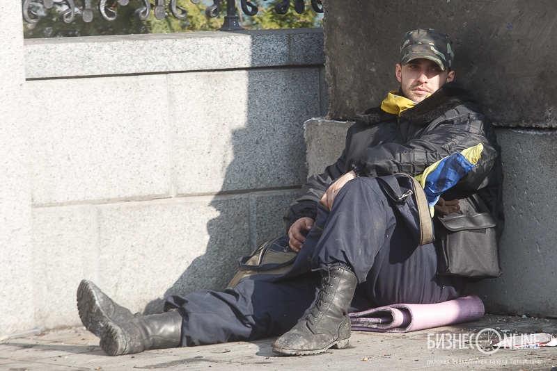 Один из бойцов майдана. На коленях лежит винтовка, завернутая во флаг