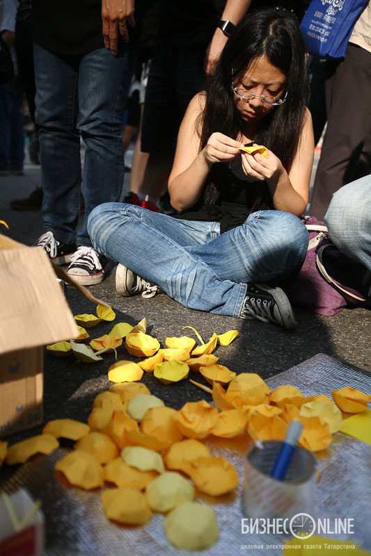 Желтые зонтики из бумаги. Рядом коробка, в которой их сотни. Вспоминается легенда про Садако Сасаки и тысячу бумажных журавликов, которые нужно сложить, чтобы исполнилось желание