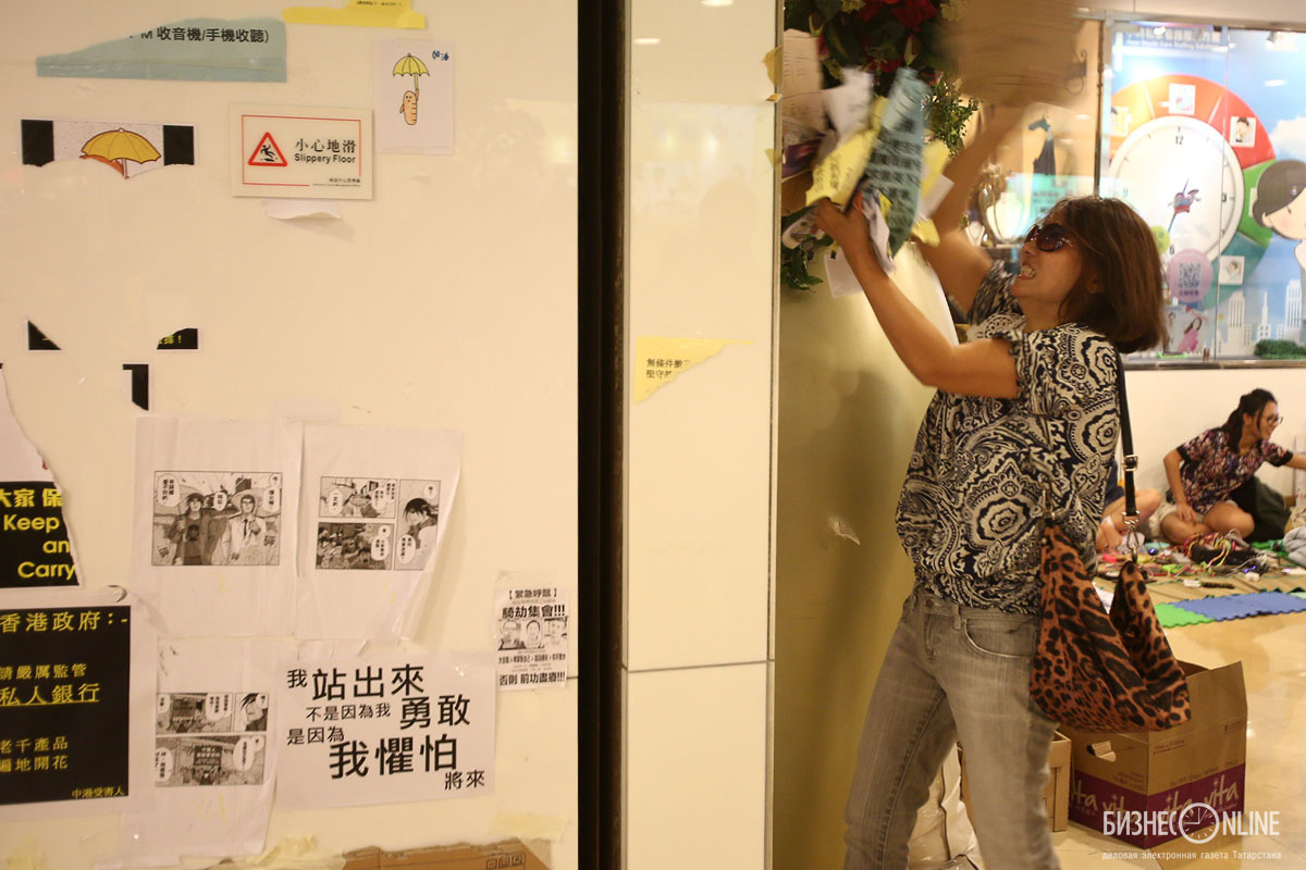 Группа людей, несогласная с оппозицией, срывает плакаты на станции метро Admiralty