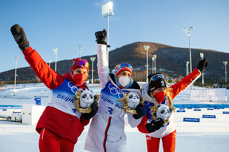 Наталья Непряева из ОКР (Россия), Тереза Йохауг из Норвегии и Тереза Стадлобер из Австрии празднуют победу в скиатлоне
