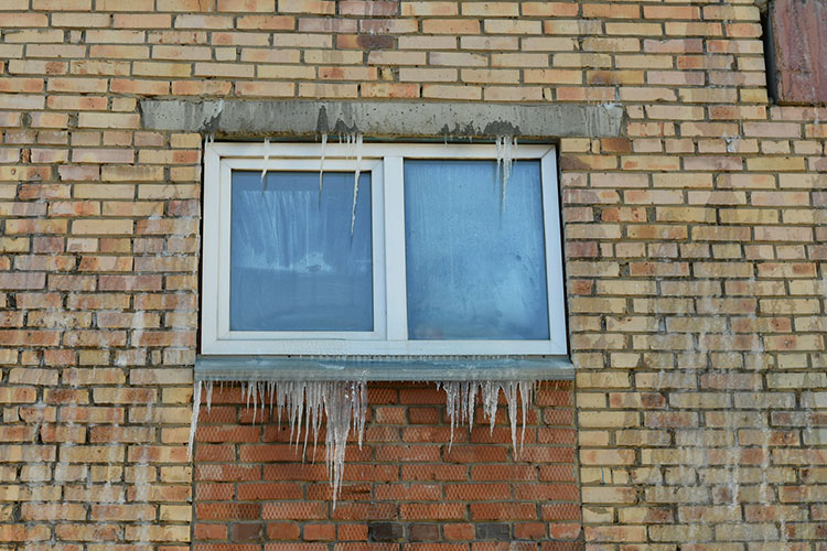 Стены покрыты коркой льда, а на балкончиках висят сосульки, которые образовались стараниями пожарных