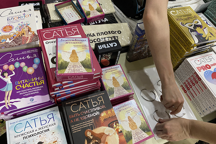 Уже после входа в «Пирамиду» небольшая толпа окружила стол с «сувениркой». В основном продавали книги о здоровых отношениях, женском очаровании, денежном достатке и других темах. Цена на них — от 1,2 тыс. рублей