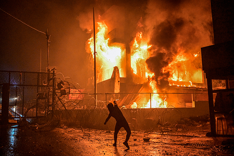 На фото: Ливан, Бейрут. Ливанский протестующий бросает камни в горящее здание недалеко от посольства США во время акции протеста в знак солидарности с народом Газы, осуждающей удары по больнице в секторе Газа