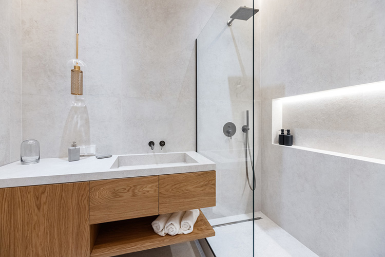 В ванной дизайнерская раковина из керамогранита, которая переходит в столешницу, совпадает с облицовкой стен