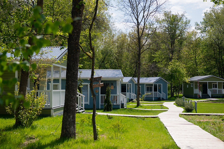 Глэмпинг «Лес и река» состоит из 11 модульных домов, рассчитанных на 4-х (те, что зеленые) и 6-х (те, что голубые) человек