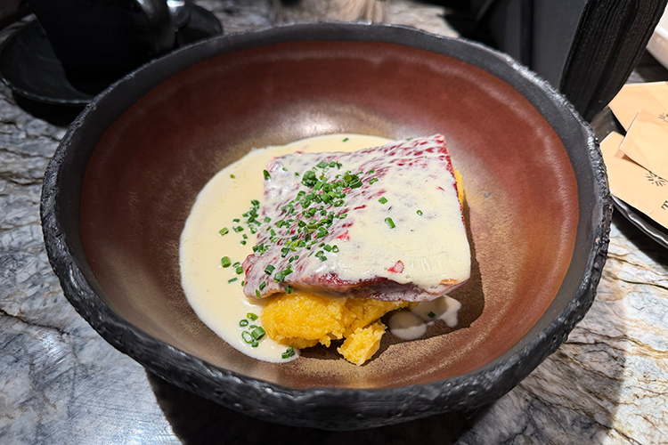 Копченая говядина, которая по виду и вкусу конина, суховата. Зато сметанно-сырный соус и мягкая сладковатая мамалыга (каша из кукурузной крупы) эту сухость технично сглаживают